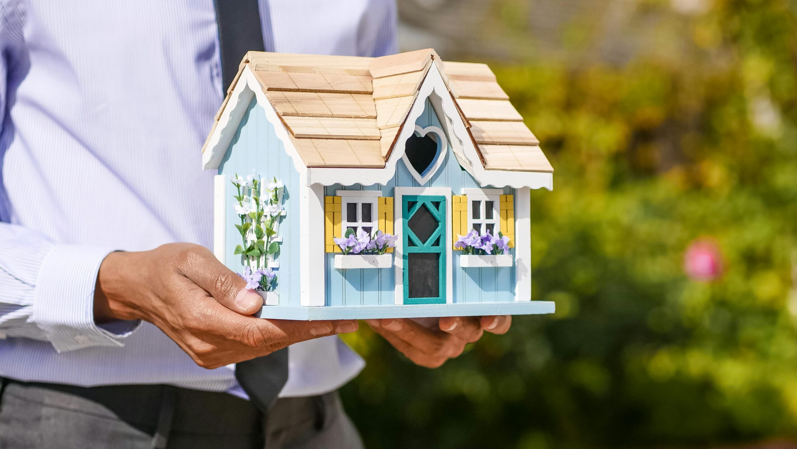 Close-up of a person holding a decorative miniature house outdoors.